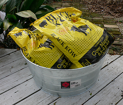 Four bags of Black Kow manure sitting my new wash tub on the deck in the backyard.  (2006)